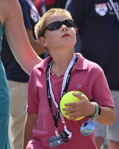 kid with tennis ball wearing sunglasses.